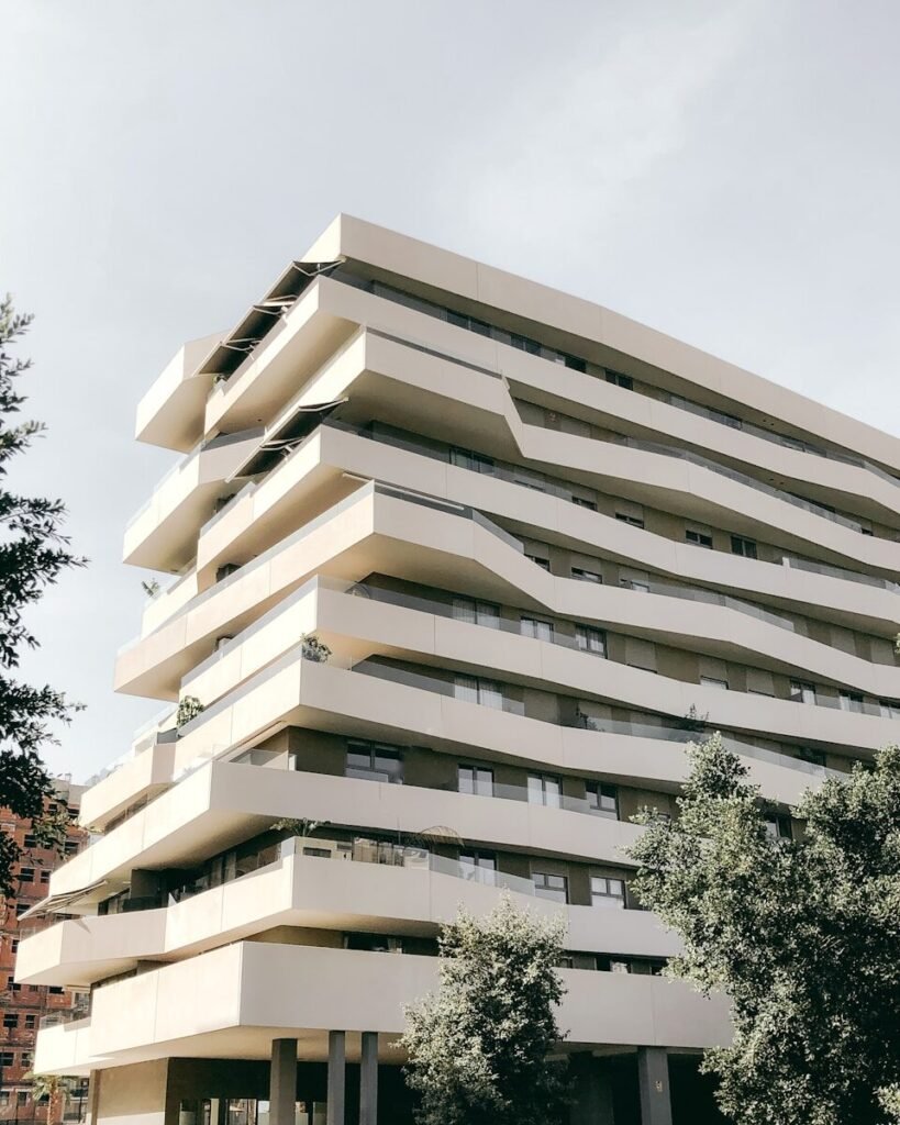 a tall white building sitting next to a lush green park